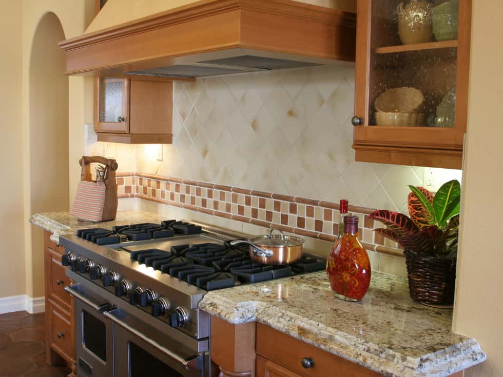 Modular Indian kitchen with tiled backsplash and chimney.