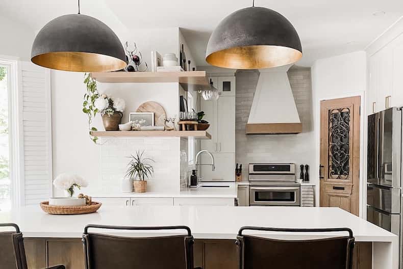 Island kitchen with bar stools, pendant lights, and glossy finish.